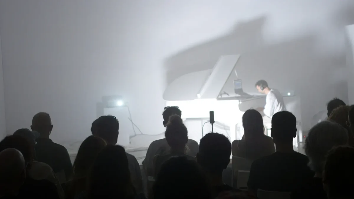 Leonardo Cincinelli performing at the piano in white haze, viewed from the audience during Per Aria
